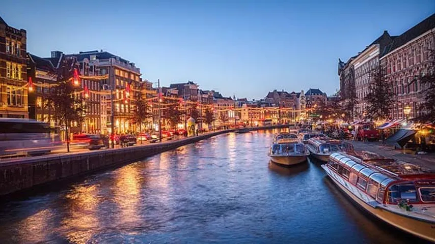 Vista nocturna de un canal con barcos turísticos en Ámsterdam. (Foto: Pixabay)